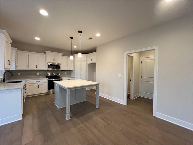 kitchen featuring sink, a kitchen island, white cabinetry, stainless steel appliances, and dark wood-type flooring