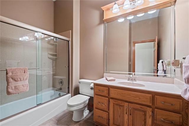 full bathroom featuring tile patterned flooring, vanity, toilet, and bath / shower combo with glass door