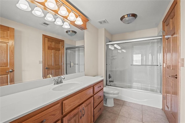 full bathroom with combined bath / shower with glass door, vanity, tile patterned flooring, and toilet