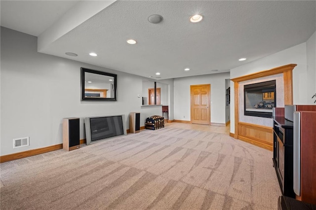 living room with light colored carpet, a textured ceiling, and a tiled fireplace