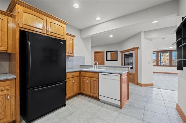 kitchen with dishwasher, black fridge, sink, decorative backsplash, and kitchen peninsula