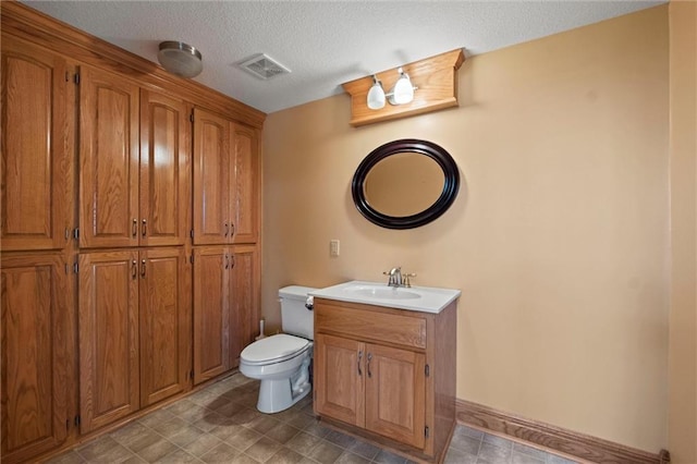 bathroom featuring a textured ceiling, vanity, and toilet