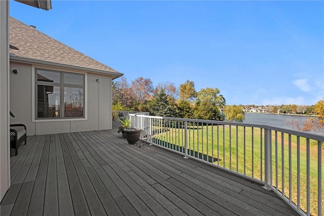 wooden terrace featuring a water view and a lawn