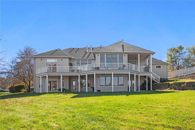 back of property with a deck, ceiling fan, and a lawn