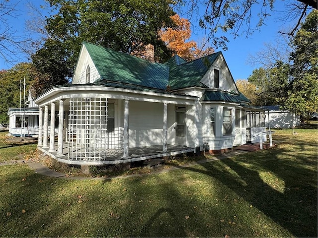 view of side of home featuring covered porch and a lawn