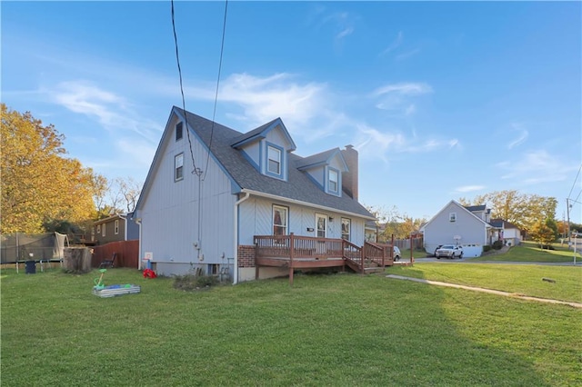 view of front facade featuring a trampoline, a wooden deck, and a front yard