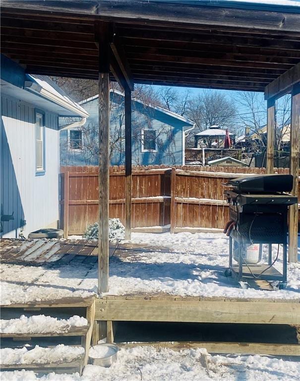 snow covered patio featuring a wooden deck and a grill