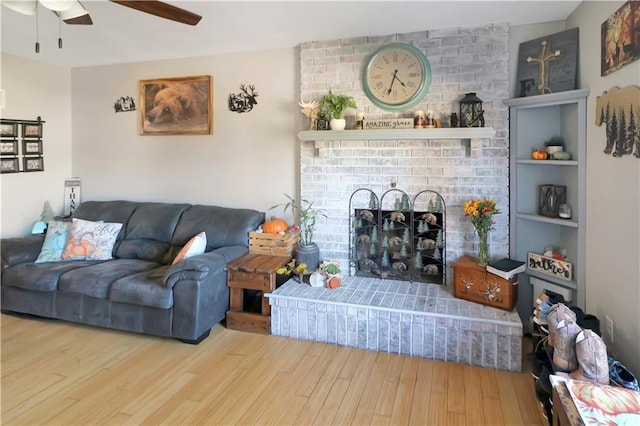 living room featuring hardwood / wood-style flooring, ceiling fan, and a fireplace