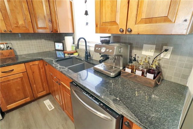 kitchen with tasteful backsplash, sink, dark stone countertops, and dishwasher