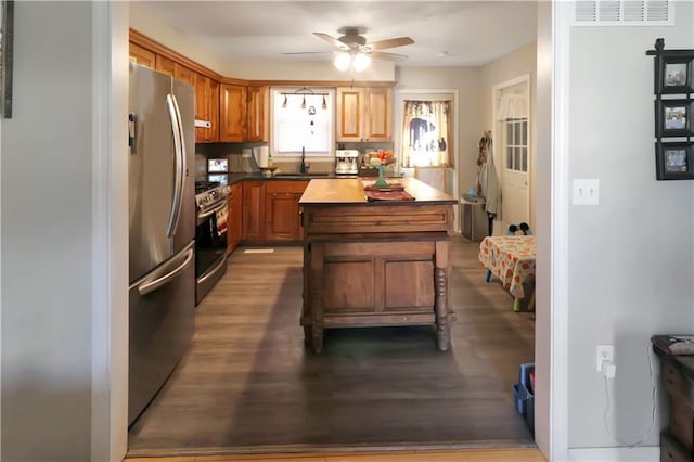 kitchen with sink, hardwood / wood-style flooring, ceiling fan, stainless steel appliances, and a center island