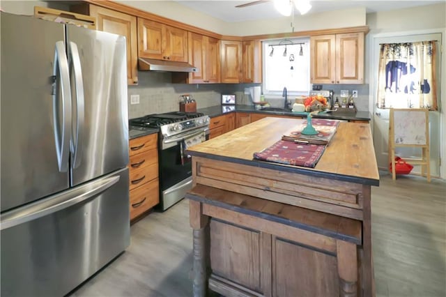 kitchen with appliances with stainless steel finishes, butcher block countertops, sink, decorative backsplash, and ceiling fan