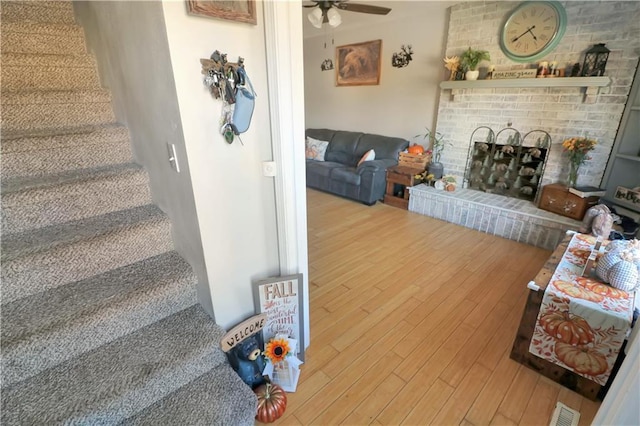 interior space with ceiling fan, wood-type flooring, and a brick fireplace