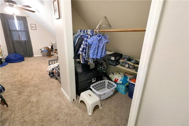 spacious closet with ceiling fan, vaulted ceiling, and carpet