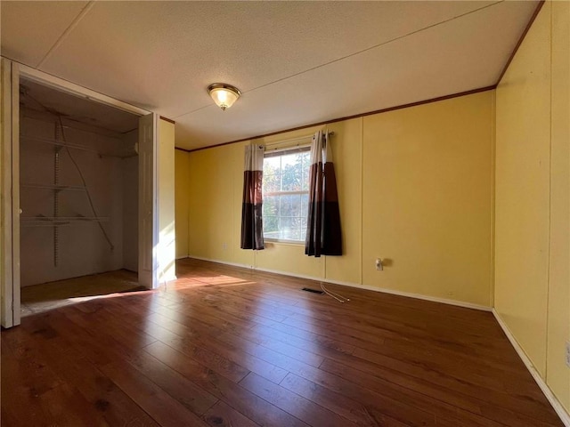 empty room with dark wood-type flooring and a textured ceiling