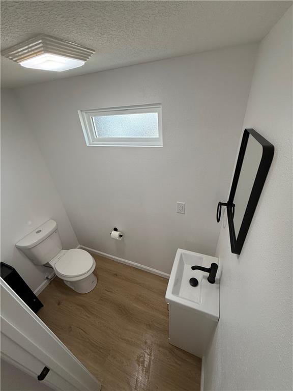 bathroom with a textured ceiling, wood-type flooring, and toilet