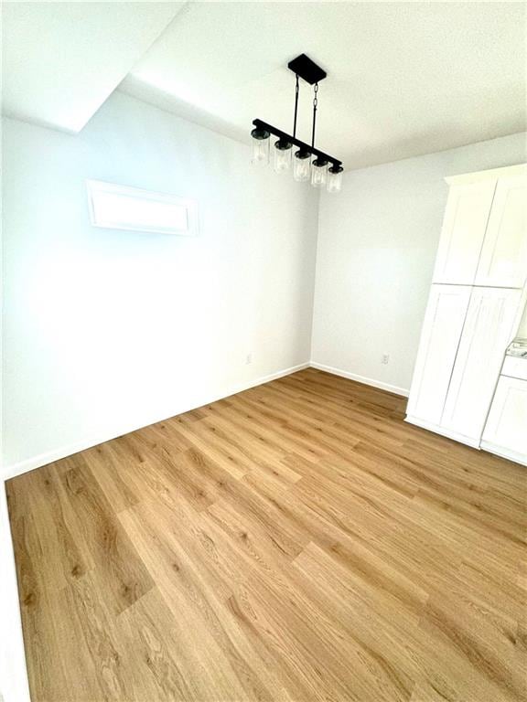 unfurnished dining area with a textured ceiling and light wood-type flooring