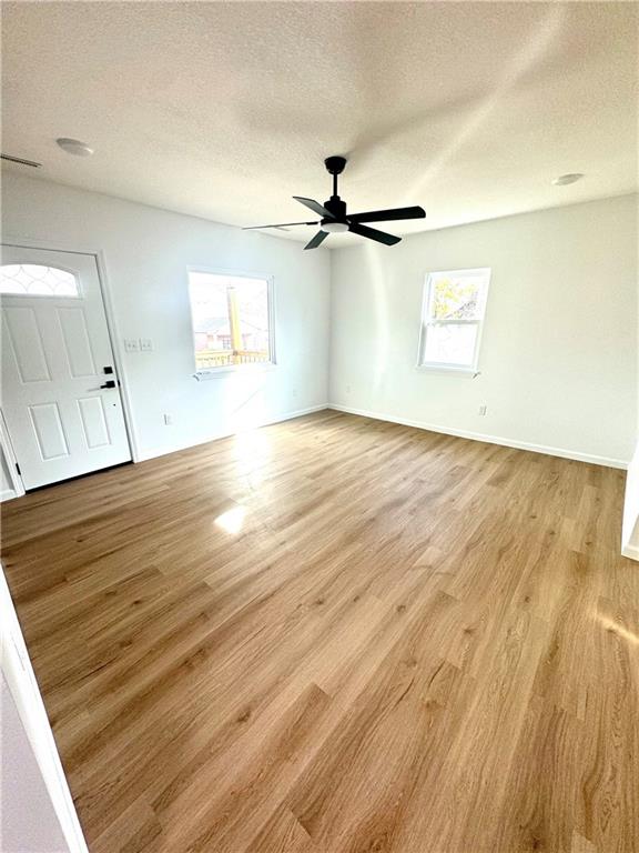 unfurnished room featuring light hardwood / wood-style floors, a textured ceiling, and ceiling fan