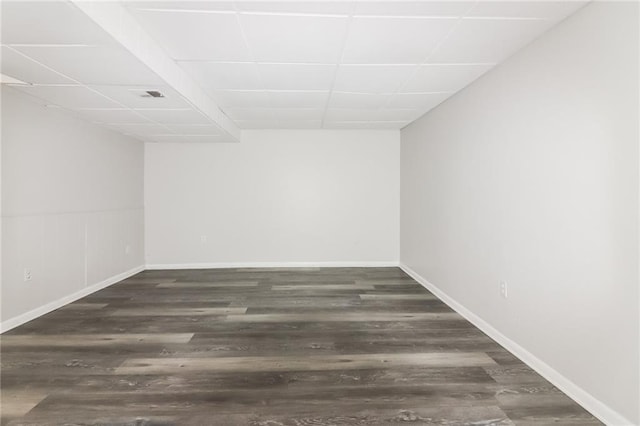 empty room with a paneled ceiling and dark hardwood / wood-style flooring