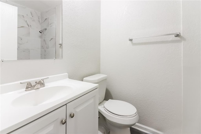 bathroom featuring vanity, toilet, and a tile shower