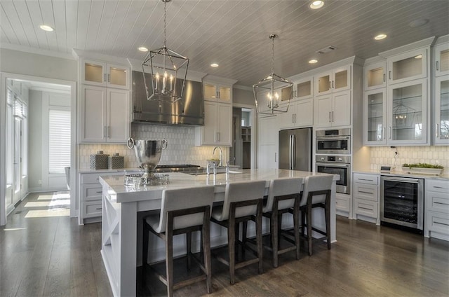 16904 Parkhill St, Overland Park, KS 66221 - kitchen with stainless steel appliances, wall chimney range hood, beverage cooler, a chandelier, and a center island with sink
