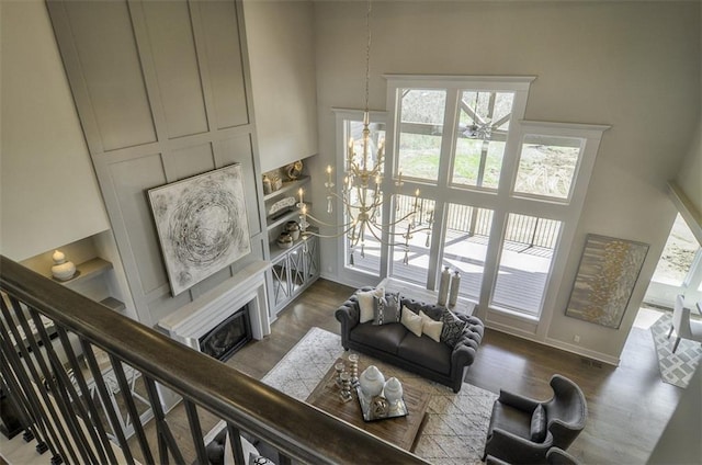 16904 Parkhill St, Overland Park, KS 66221 - living room featuring a glass covered fireplace, wood finished floors, a chandelier, and a high ceiling