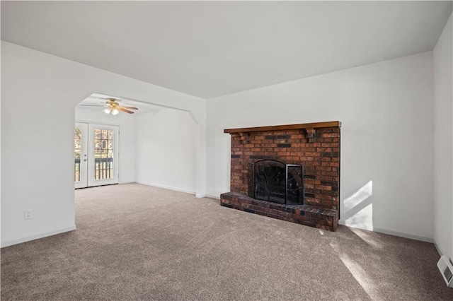 unfurnished living room with carpet flooring, ceiling fan, a fireplace, and french doors