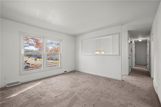 carpeted empty room with an inviting chandelier