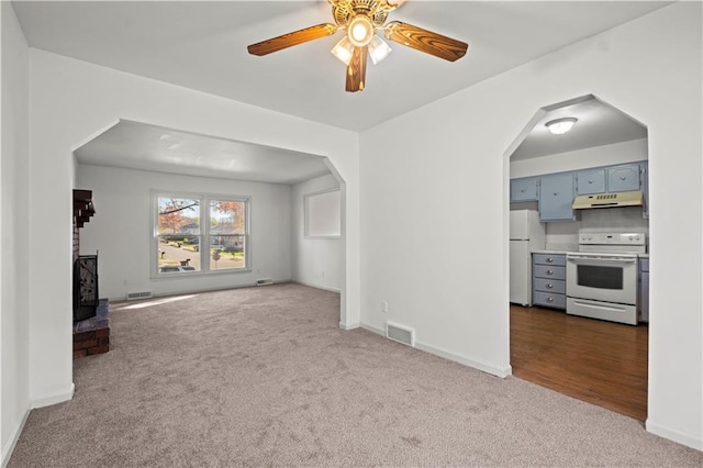 unfurnished living room with carpet flooring, ceiling fan, and a wood stove