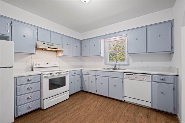 kitchen with hardwood / wood-style floors, gray cabinetry, white appliances, and sink