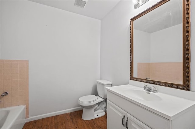 bathroom with hardwood / wood-style flooring, vanity, toilet, and a washtub