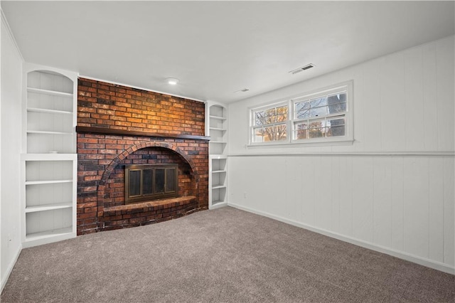 unfurnished living room with carpet, a brick fireplace, and built in features