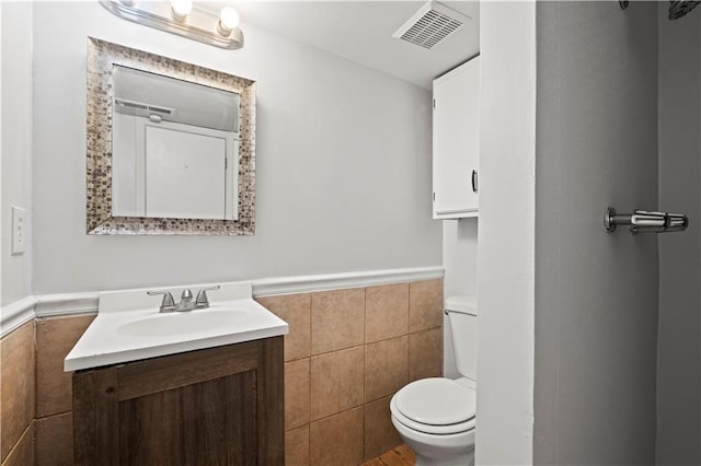 bathroom with vanity, tile walls, and toilet