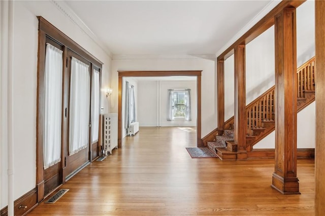 foyer entrance featuring radiator, crown molding, french doors, and light hardwood / wood-style floors