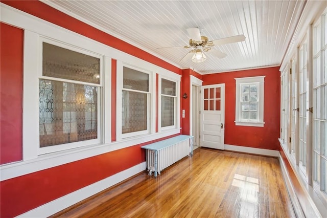 unfurnished sunroom with ceiling fan, wooden ceiling, and radiator