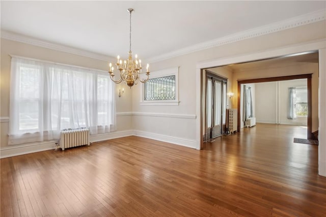 unfurnished room featuring radiator heating unit, crown molding, a healthy amount of sunlight, and wood-type flooring