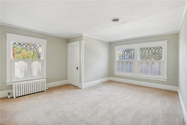 empty room featuring light colored carpet, crown molding, and radiator