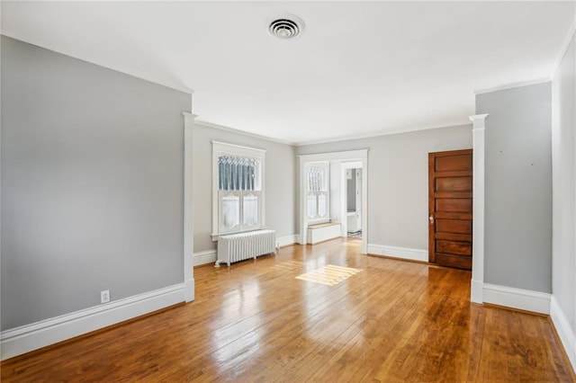 spare room with radiator heating unit, light wood-type flooring, and crown molding