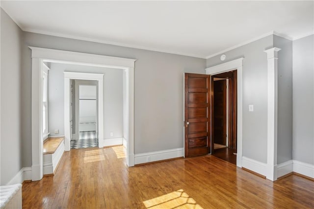 spare room with decorative columns, wood-type flooring, and ornamental molding