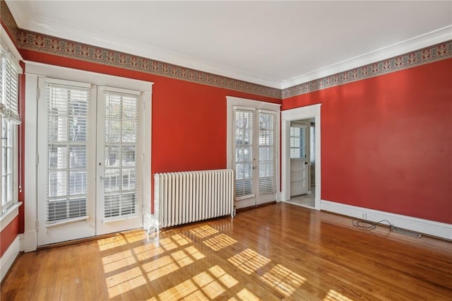 empty room featuring radiator heating unit, ornamental molding, and hardwood / wood-style flooring