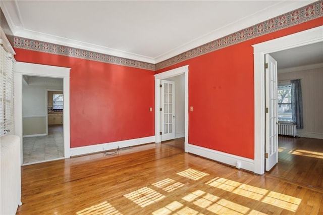 empty room featuring hardwood / wood-style floors, crown molding, and radiator