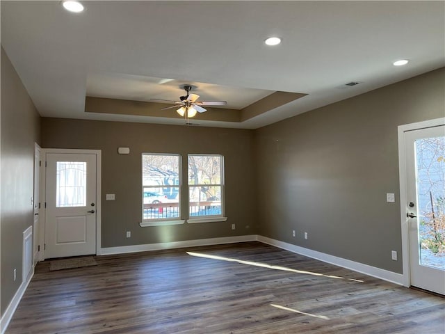 foyer entrance with ceiling fan, a healthy amount of sunlight, dark hardwood / wood-style flooring, and a tray ceiling