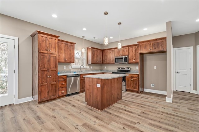 kitchen with stainless steel appliances, a center island, light hardwood / wood-style floors, and hanging light fixtures