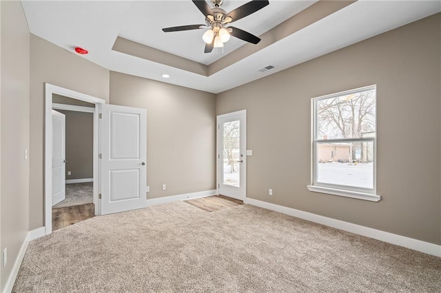 unfurnished room featuring a raised ceiling, carpet flooring, and ceiling fan