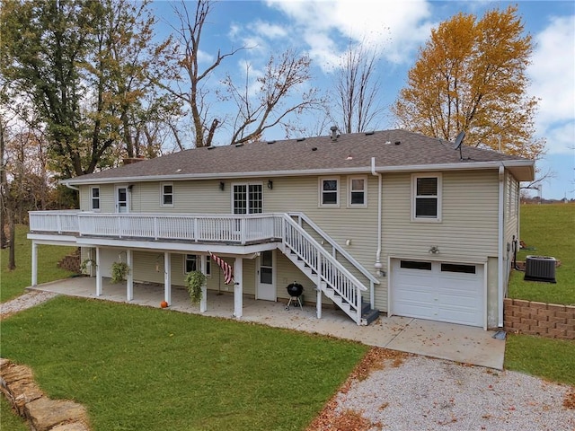 back of property featuring a deck, central AC unit, a garage, and a lawn