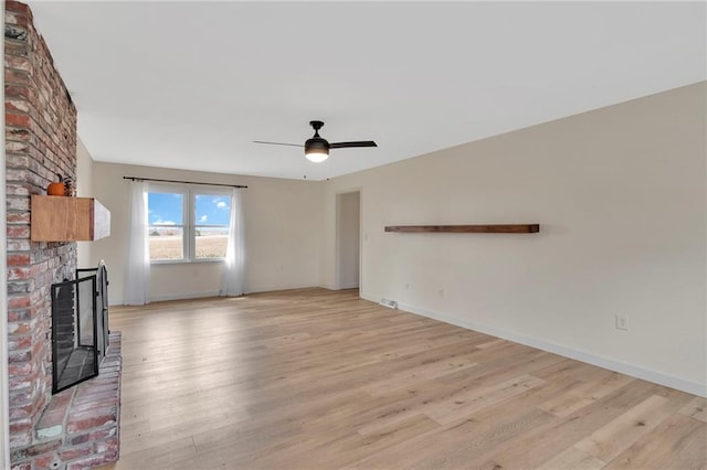 unfurnished living room with light hardwood / wood-style floors, ceiling fan, and a brick fireplace