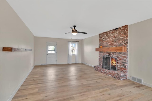 unfurnished living room with ceiling fan, light wood-type flooring, and a brick fireplace