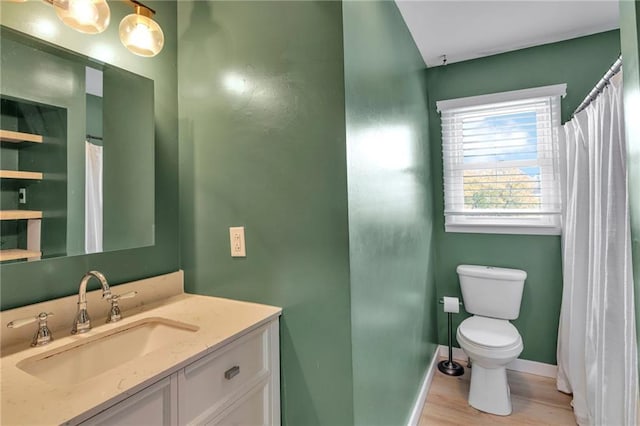 bathroom with toilet, vanity, and wood-type flooring