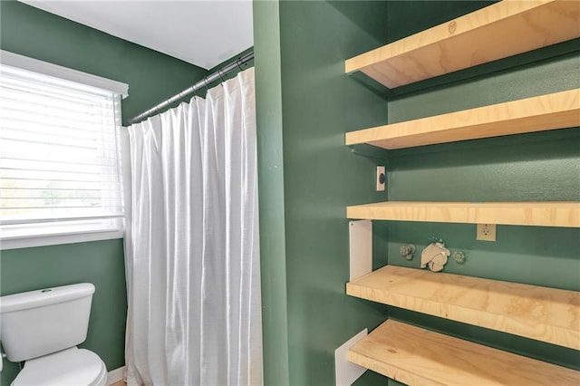 bathroom featuring toilet and curtained shower