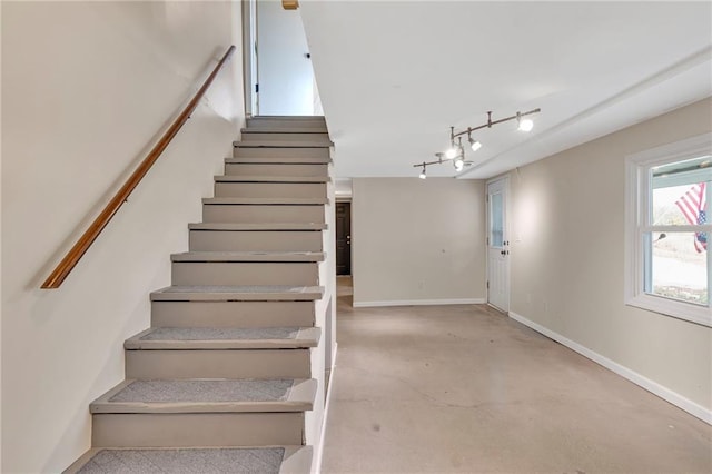 stairway with track lighting and concrete flooring