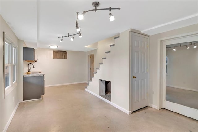 basement featuring sink and rail lighting